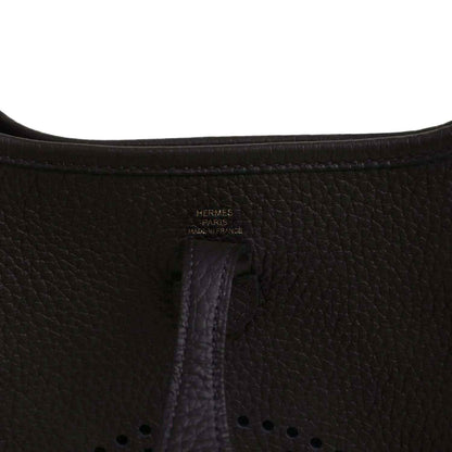 Black leather Evelyne TPM bag close-up of “Hermes Paris” stamp and vertical seam.