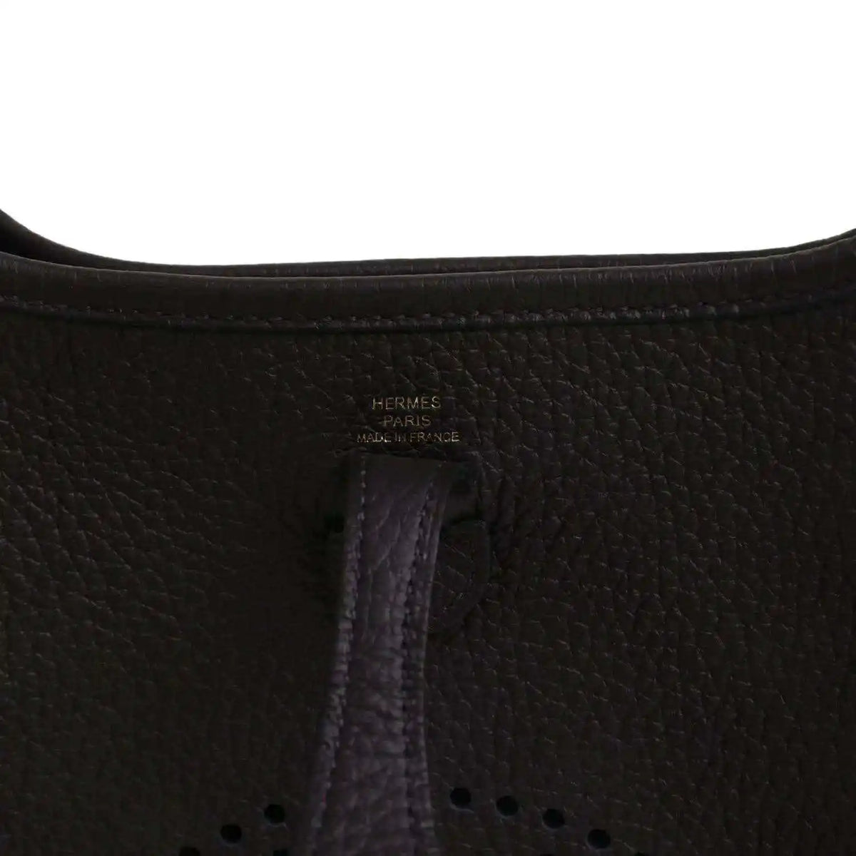 Black leather Evelyne TPM bag close-up of “Hermes Paris” stamp and vertical seam.