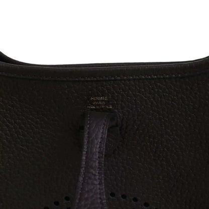 Black leather Evelyne TPM bag close-up of “Hermes Paris” stamp and vertical seam.