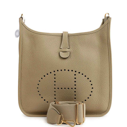 Small tan leather shoulder bag with perforated logo panel, front tab, and gold hardware