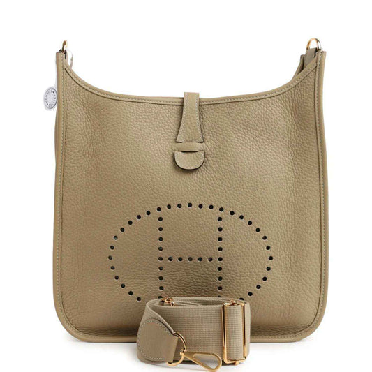 Small tan leather shoulder bag with perforated logo panel, front tab, and gold hardware