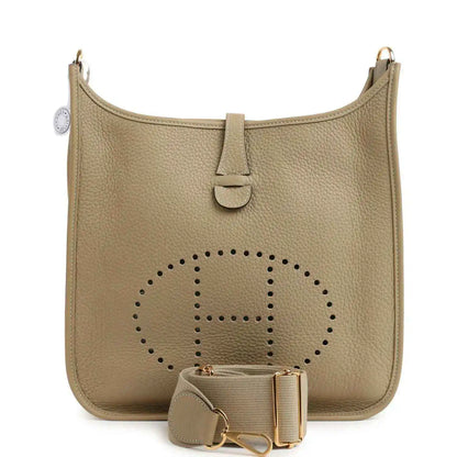 Small tan leather shoulder bag with perforated logo panel, front tab, and gold hardware
