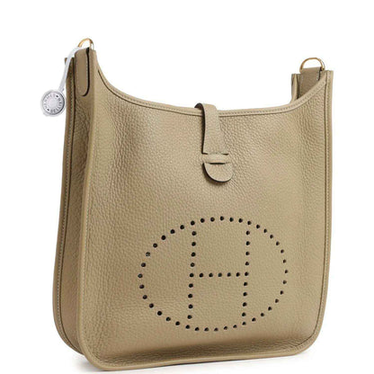 Small tan leather shoulder bag with perforated logo and adjustable strap at side ring