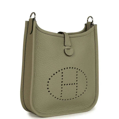 Sage green leather crossbody bag with perforated Evelyne logo and top handle