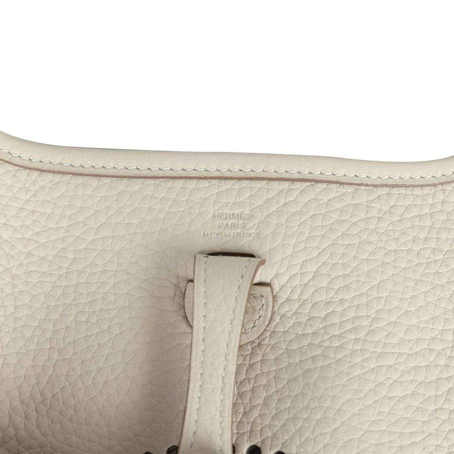 Light cream leather bag close-up of strap attachment and embossed logo stamp