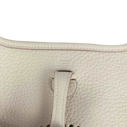 Light cream leather bag close-up of strap attachment and embossed logo stamp