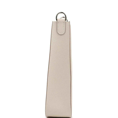 Light beige leather bag with tall strap, hanging D-ring, and silver-tone hardware