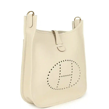 Light cream hobo-style shoulder bag with perforated logo, snap closure flap and gold-tone rings.