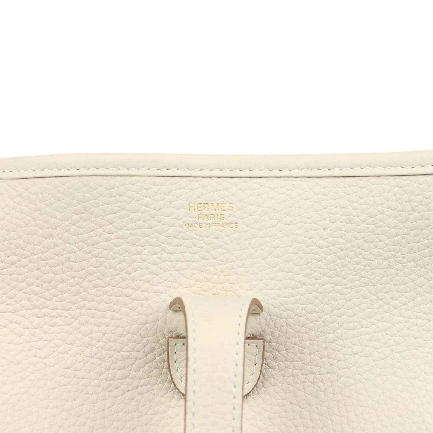 Close-up of cream leather bag interior patch and stitched side seams with small gold logo.