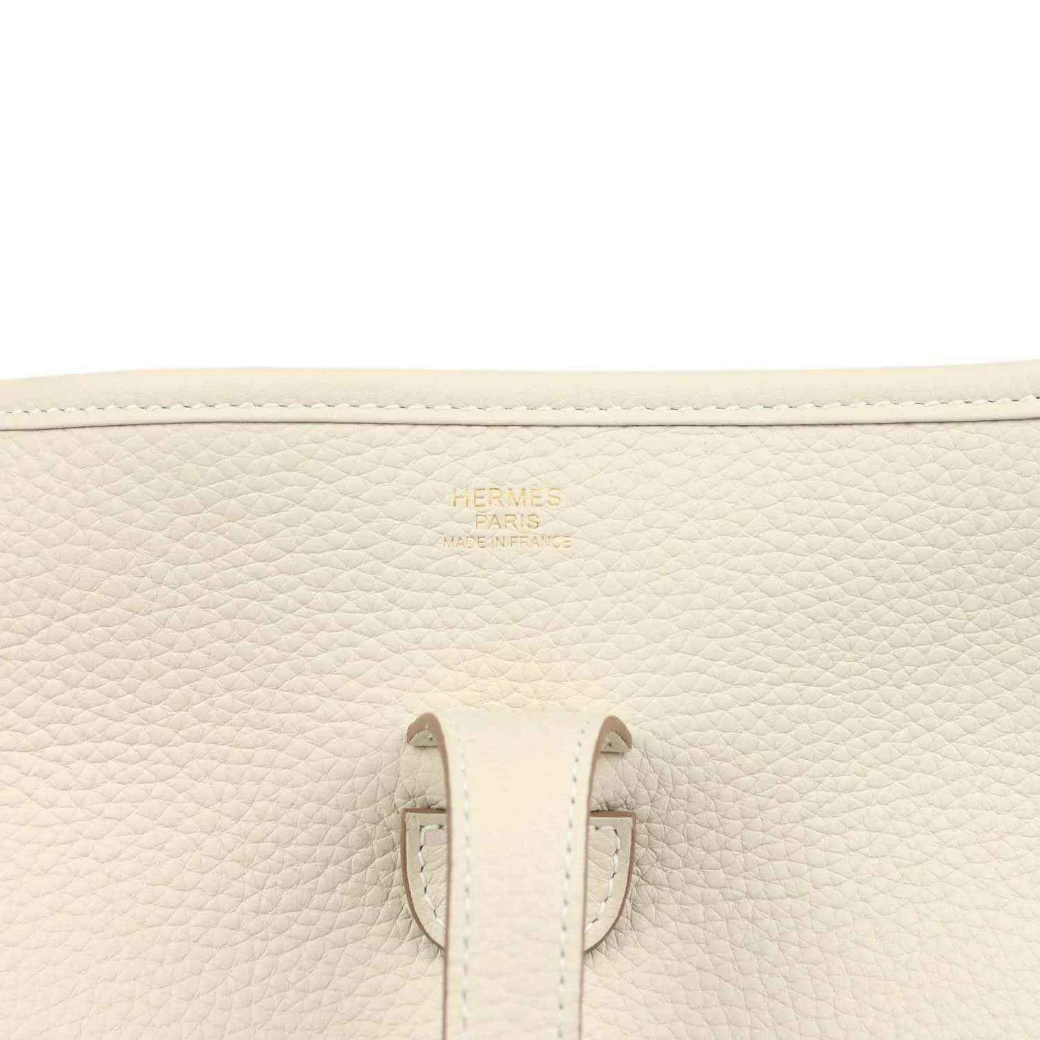 Close-up of cream leather bag interior patch and stitched side seams with small gold logo.