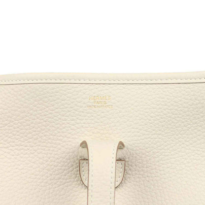 Close-up of cream leather bag interior patch and stitched side seams with small gold logo.