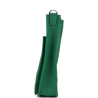 Green leather crossbody bag side view with top handle and curved base