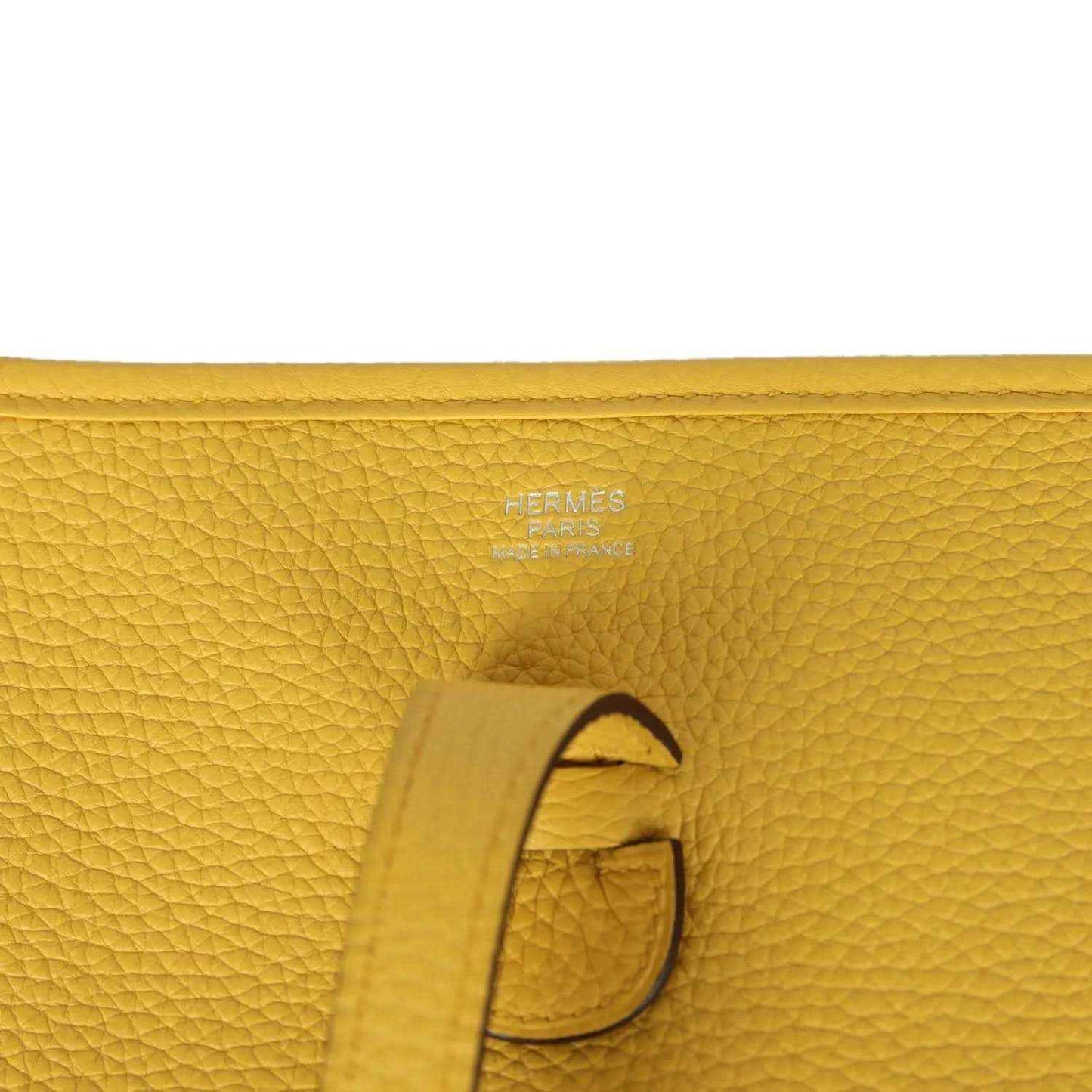 Hermès embossed yellow leather tab detail with strap and stitching