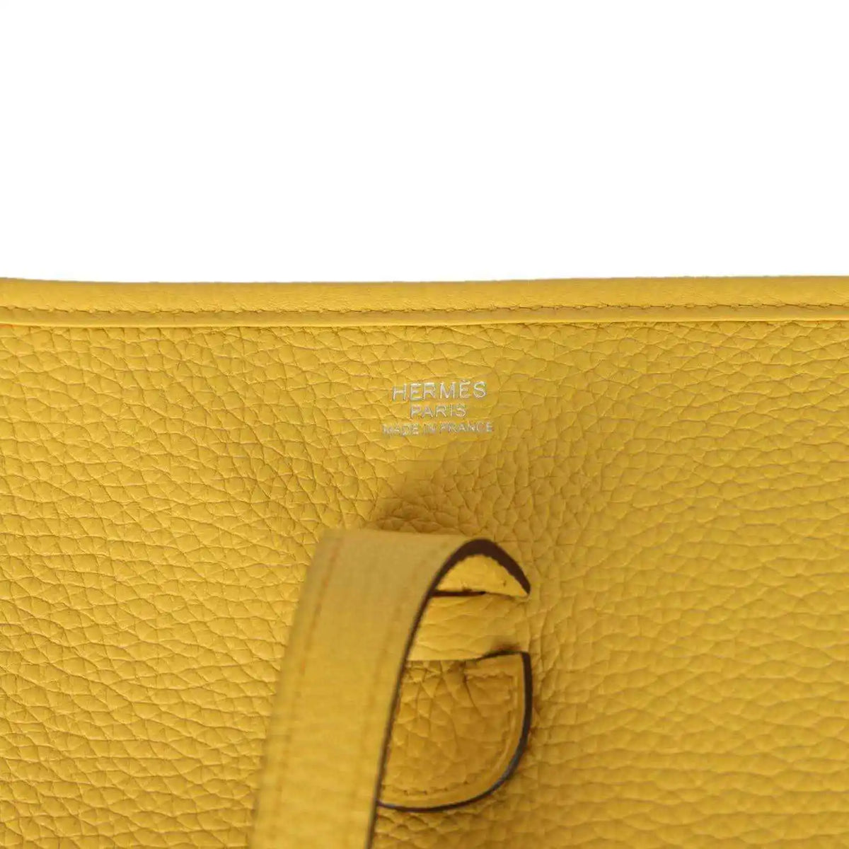 Hermès embossed yellow leather tab detail with strap and stitching