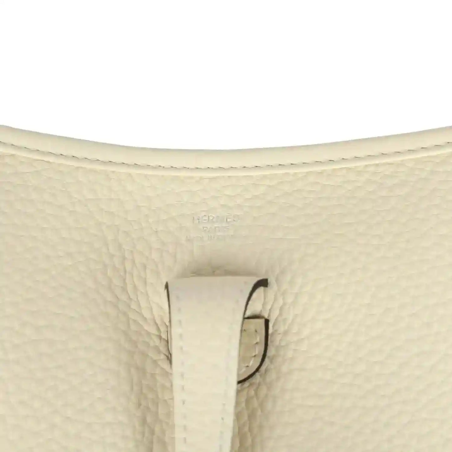 Close-up of cream pebbled leather bag with stitched tab and loop hardware