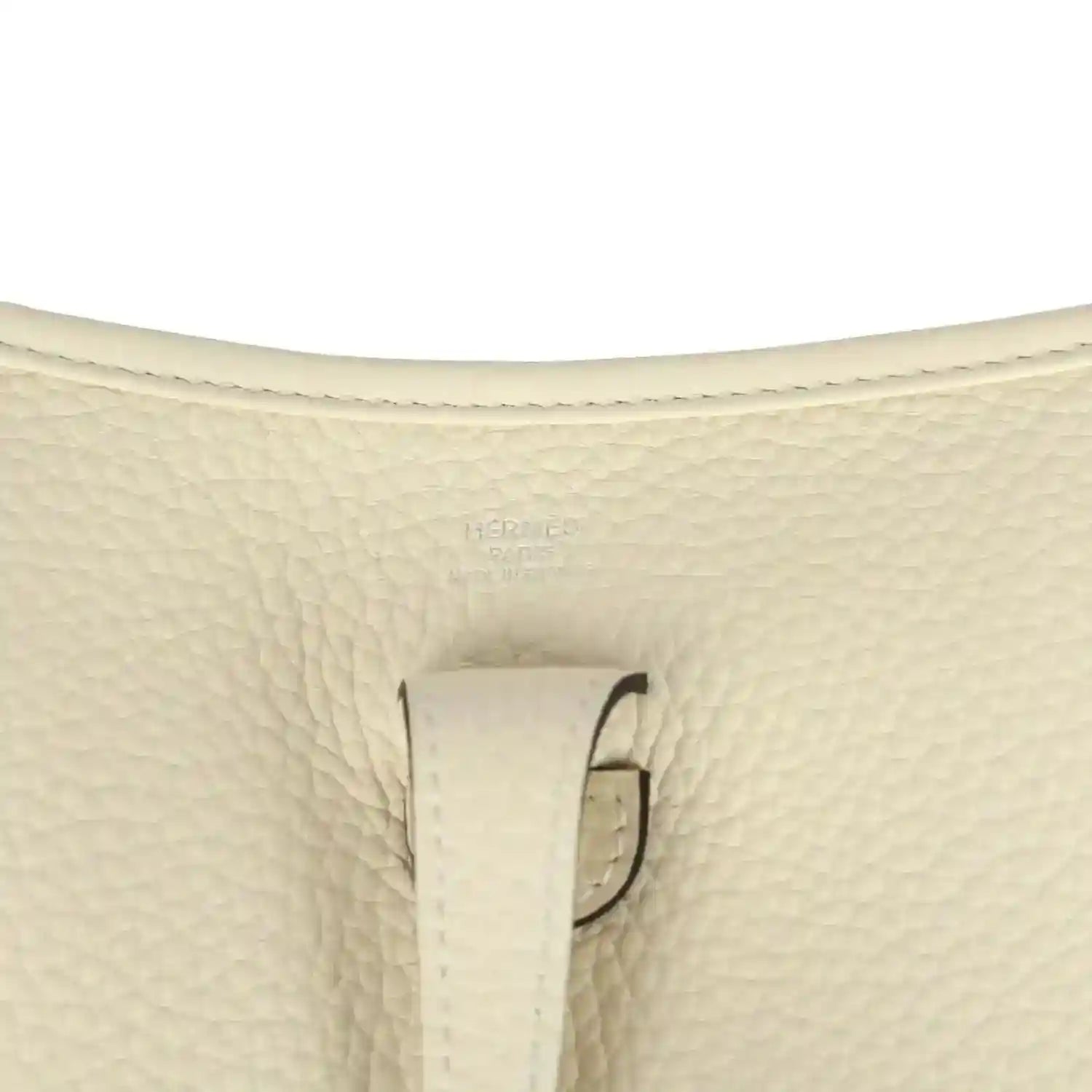 Close-up of cream pebbled leather bag with stitched tab and loop hardware