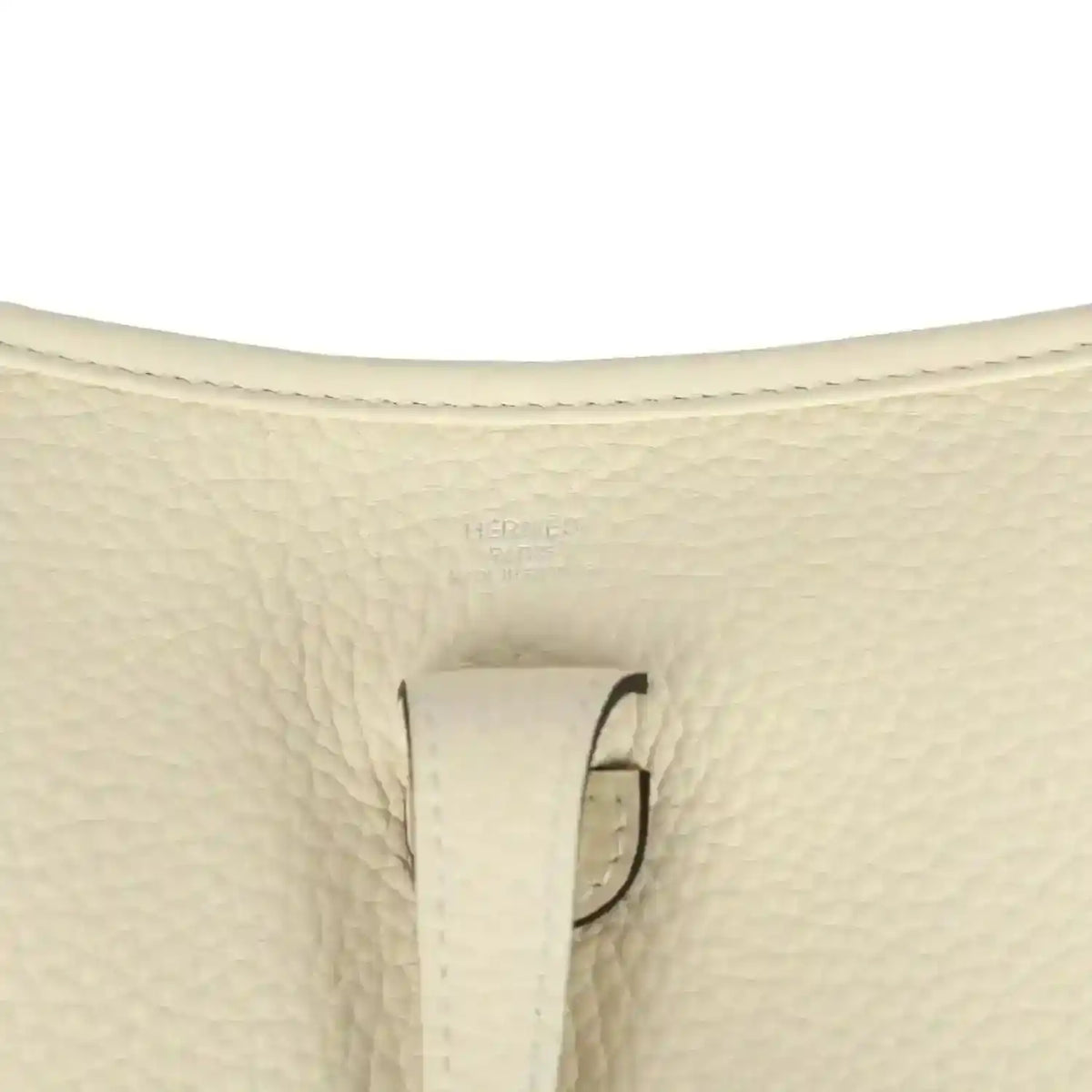 Close-up of cream pebbled leather bag with stitched tab and loop hardware