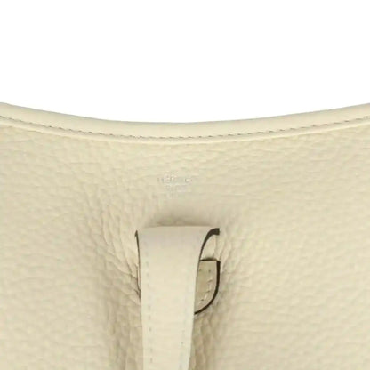 Close-up of cream pebbled leather bag with stitched tab and loop hardware