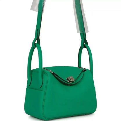 Mini green leather handbag with curved top flap and front seam detail