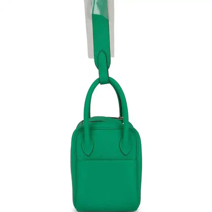 Mini green leather handbag with two short handles and compact body