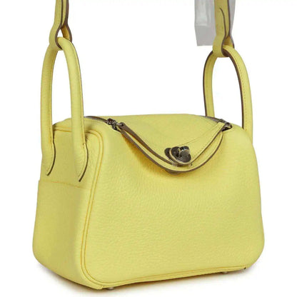 Hermes mini Lindy handbag in textured yellow leather with curved shoulder straps.