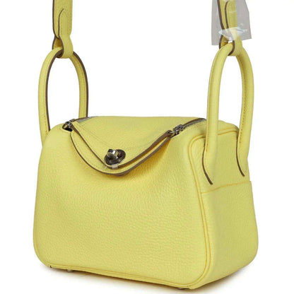 Hermes mini Lindy handbag in textured yellow leather, side view of flap and strap.