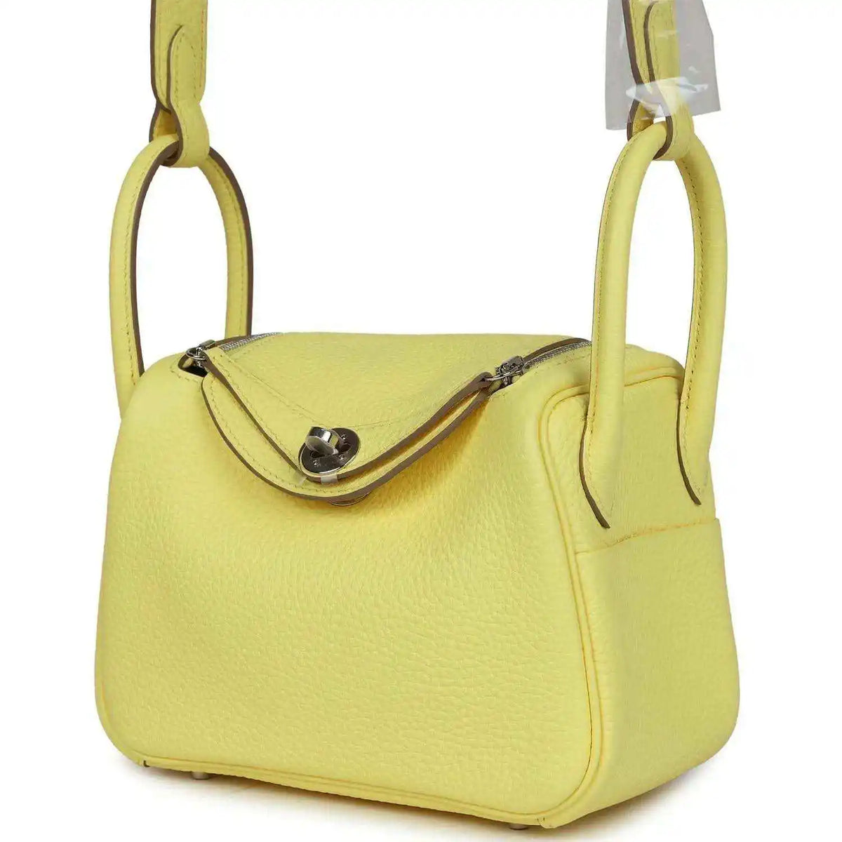Hermes mini Lindy handbag in textured yellow leather, side view of flap and strap.