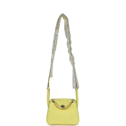 Hermes mini Lindy handbag in textured yellow leather with long shoulder strap and flap.