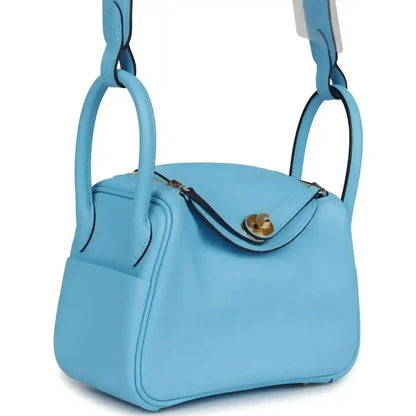 Mini light blue leather handbag with curved top flap and gold-tone clasp