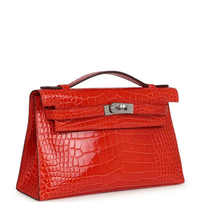 Orange crocodile-texture Kelly pochette with front flap, top handle, and clasp visible