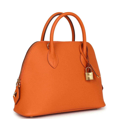 Orange leather handbag with top handles, gold padlock clasp and dangling key, detachable strap.