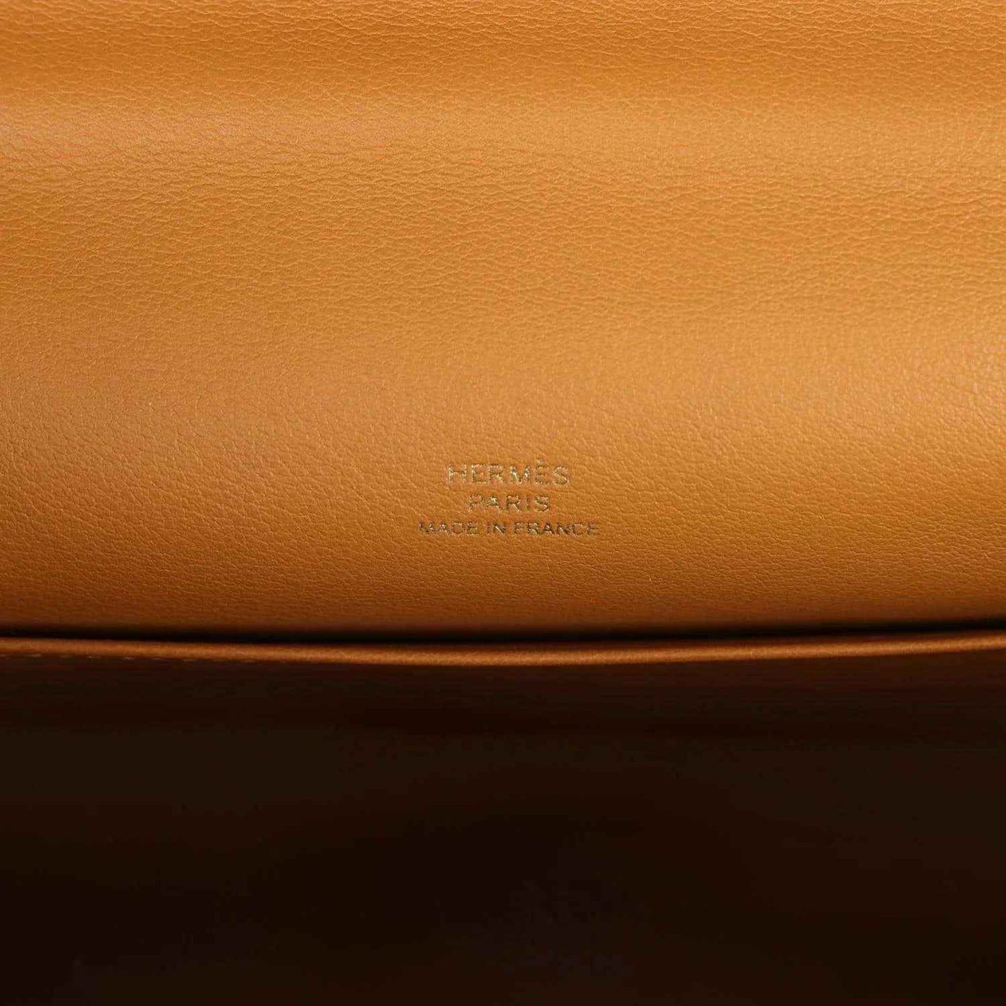 Tan leather handbag close-up with embossed Hermes logo