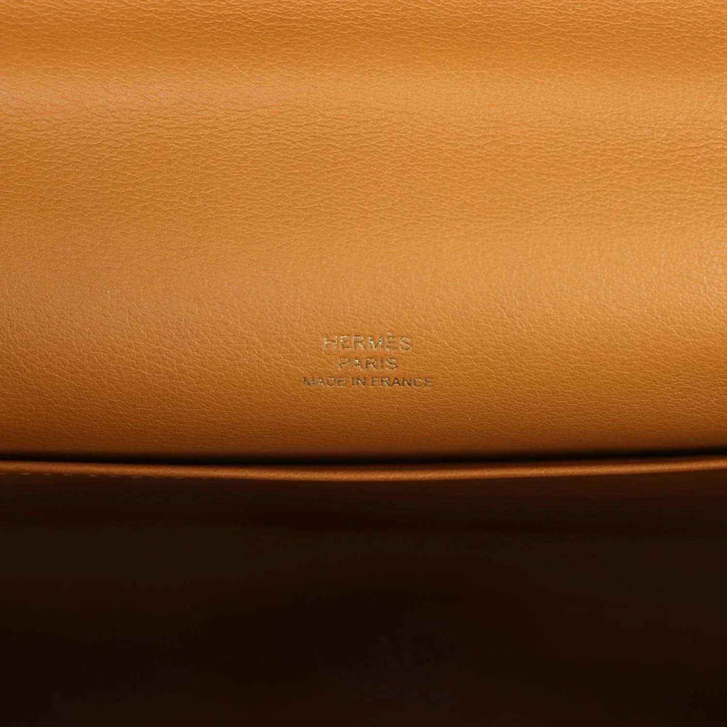 Tan leather handbag close-up with embossed Hermes logo