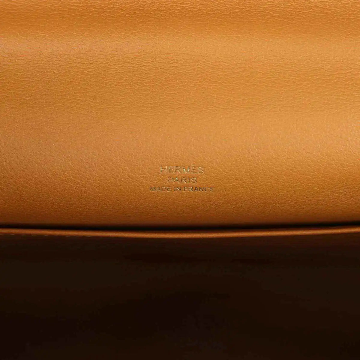 Tan leather handbag close-up with embossed Hermes logo