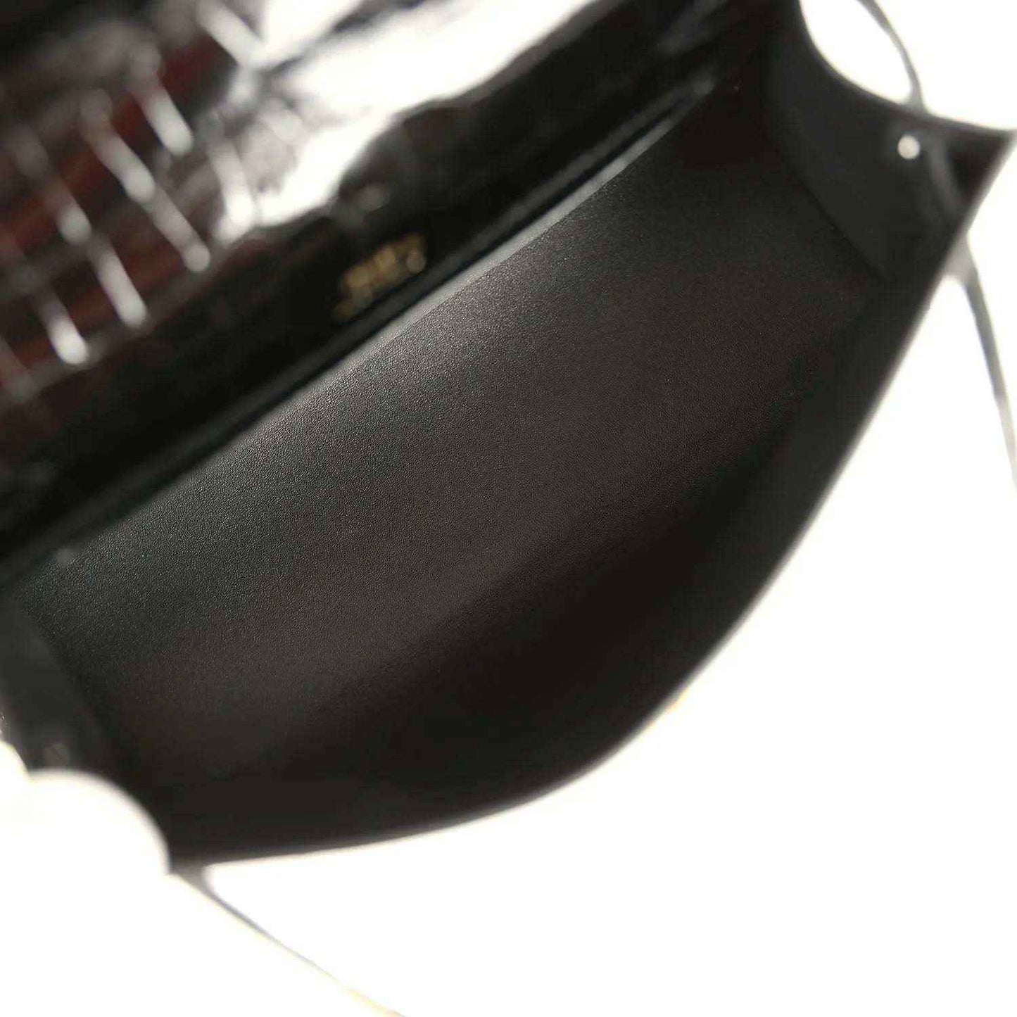 Black leather-lined interior of crocodile handbag with gold hardware corner