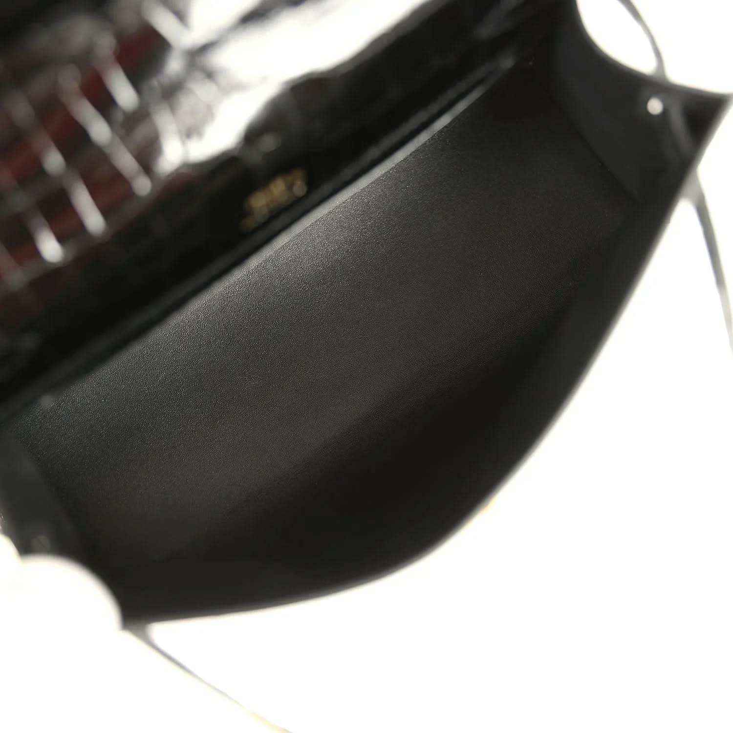 Black leather-lined interior of crocodile handbag with gold hardware corner