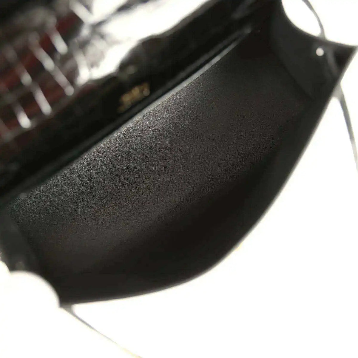 Black leather-lined interior of crocodile handbag with gold hardware corner