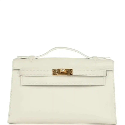 White leather clutch bag with top handle, front flap, and gold turn-lock clasp