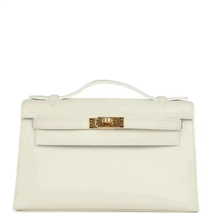 White leather clutch bag with top handle, front flap, and gold turn-lock clasp