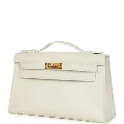 White leather clutch bag with front flap, top handle, and gold turn-lock clasp