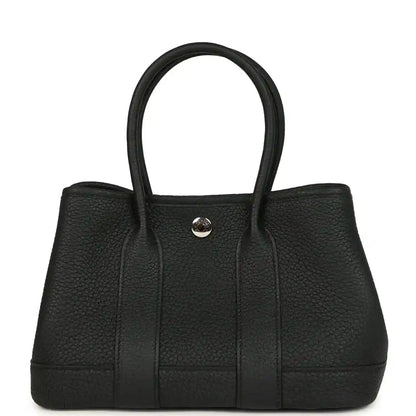 Black leather tote bag with top handles and central snap closure