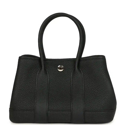 Black leather tote bag with top handles and central snap closure