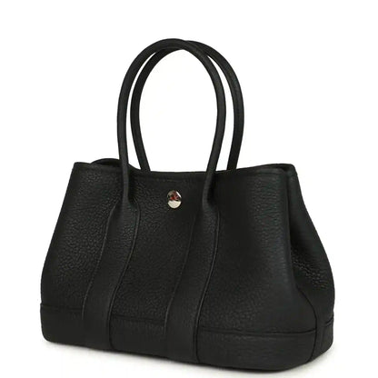 Black leather tote bag with top handles and central snap hardware