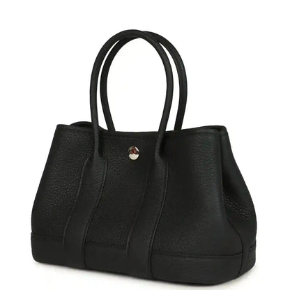 Black leather tote bag with top handles and central snap hardware