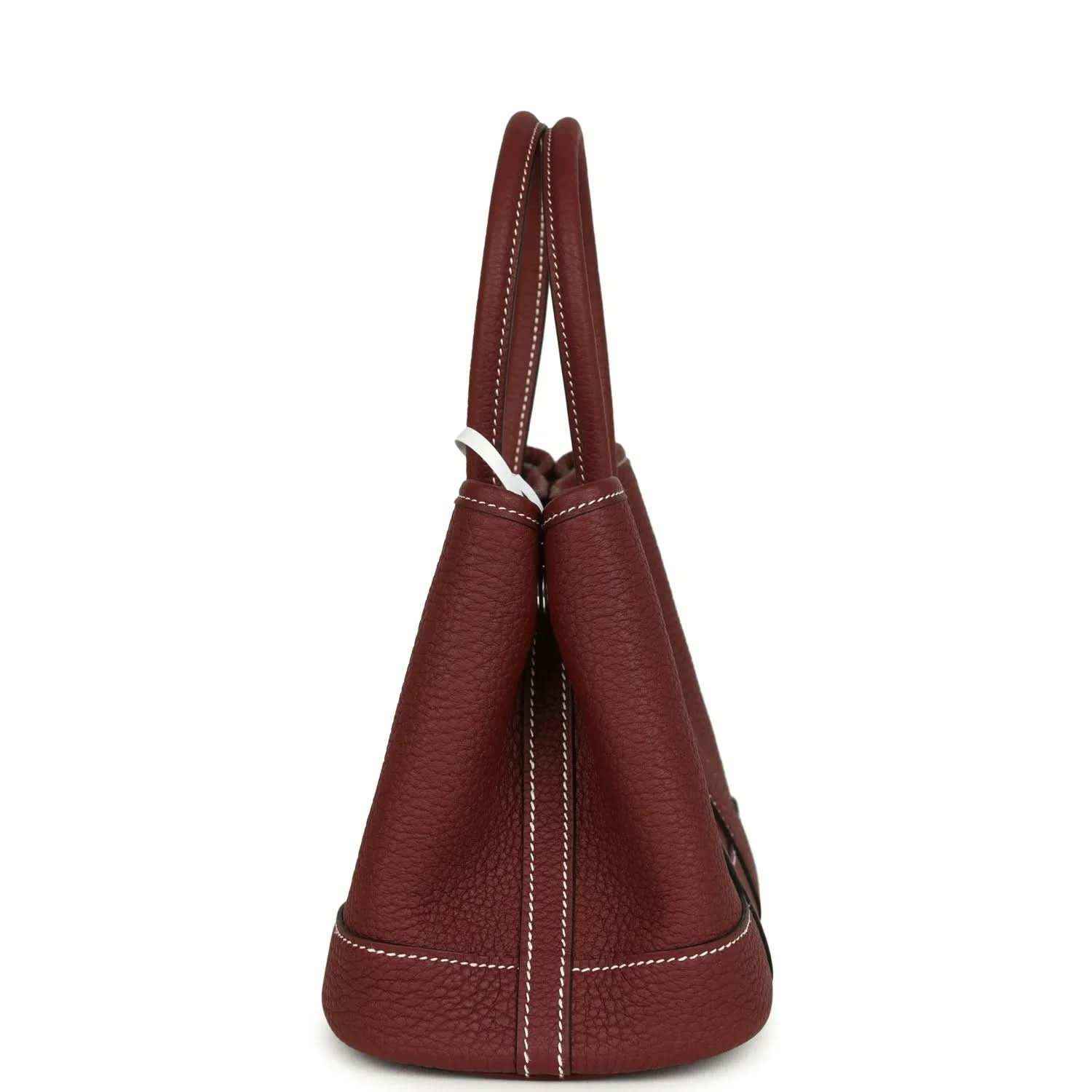 Red leather tote bag side view with stitched seams and loop handle.