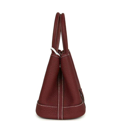 Red leather tote bag side view with stitched seams and loop handle.