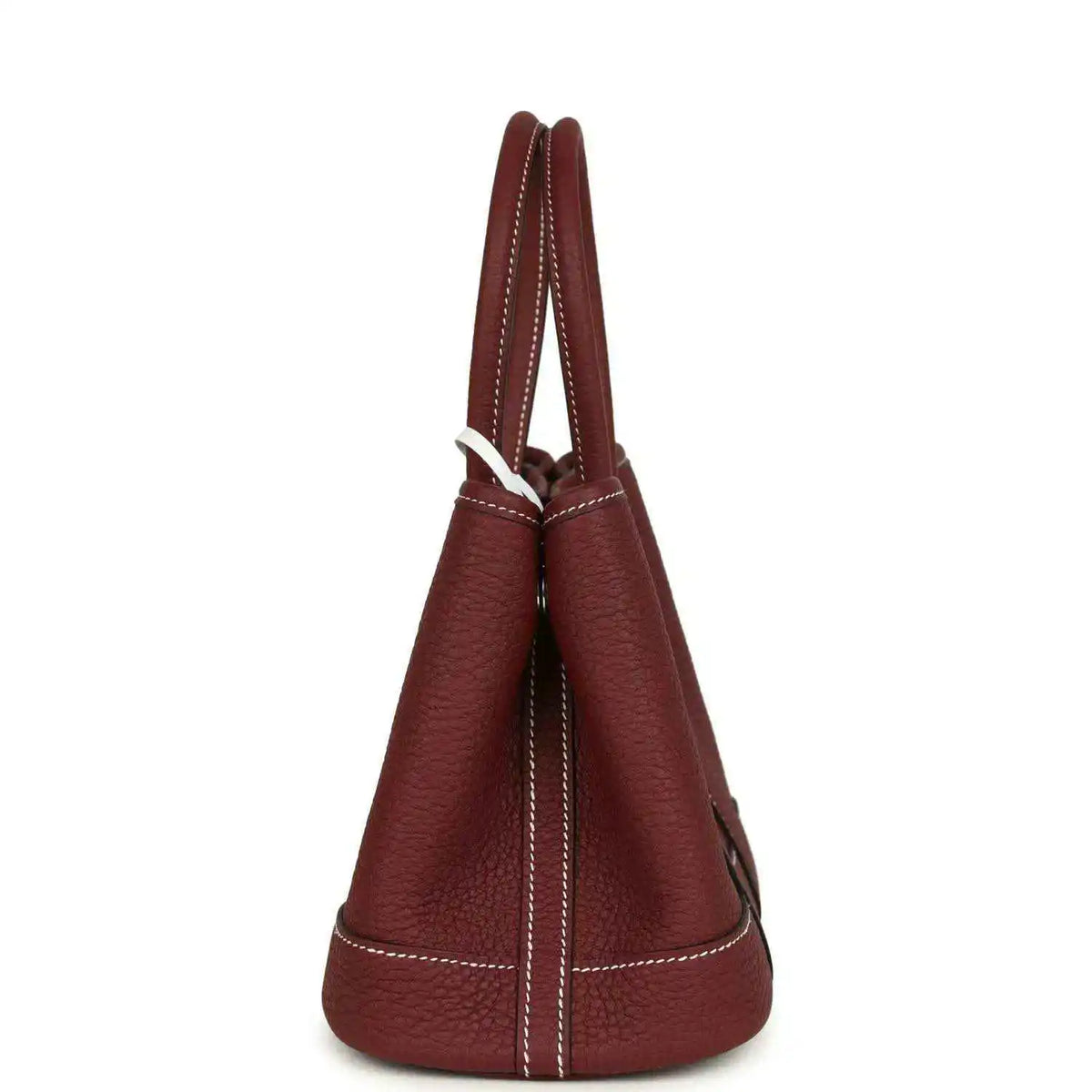 Red leather tote bag side view with stitched seams and loop handle.