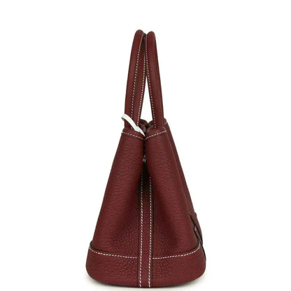 Red leather tote bag side view with stitched seams and loop handle.