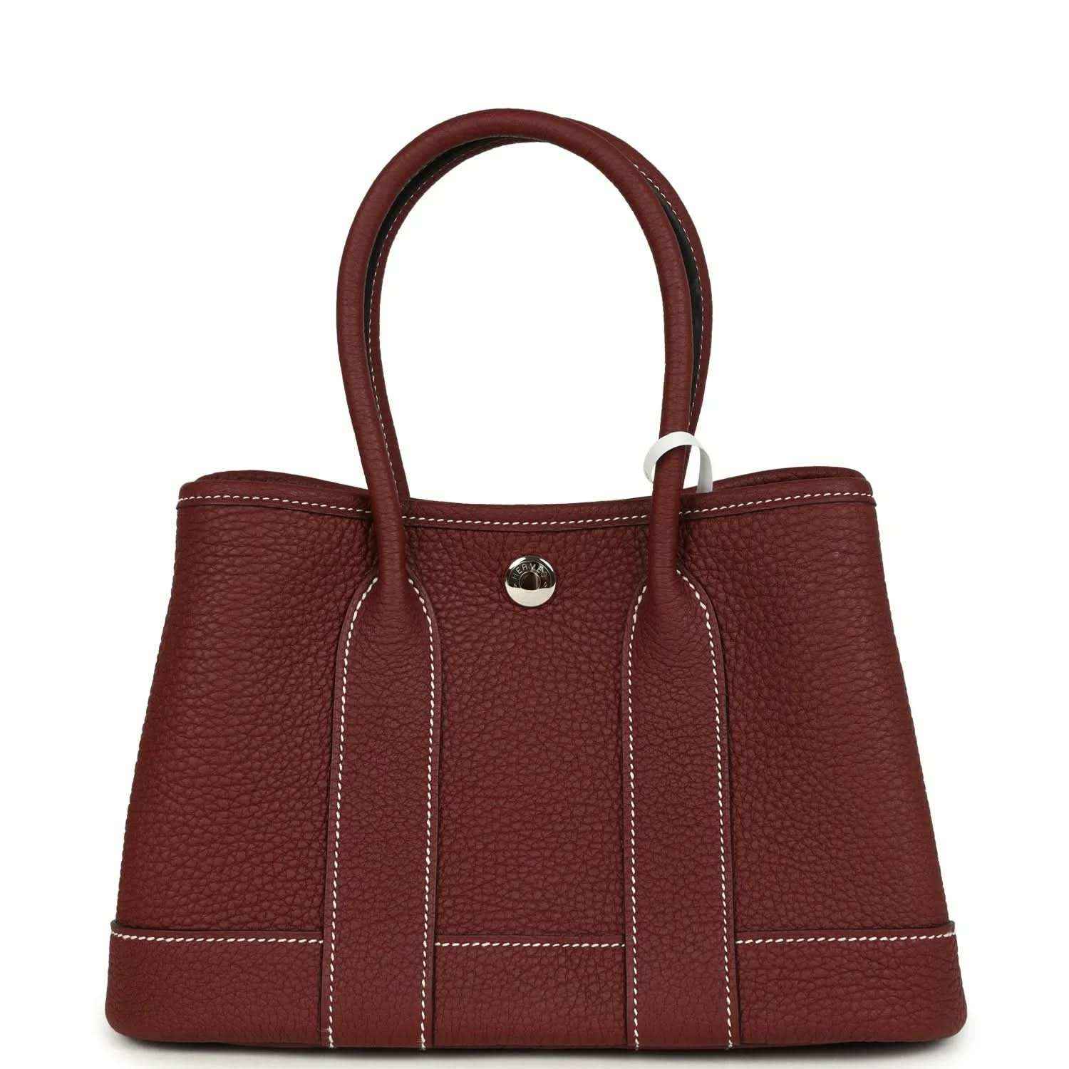 Red leather tote bag with top handles, front snap button, and stitched front panels.