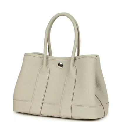 Hermes Garden Party Neo 23 tote bag angled view in light beige leather with front snap tab